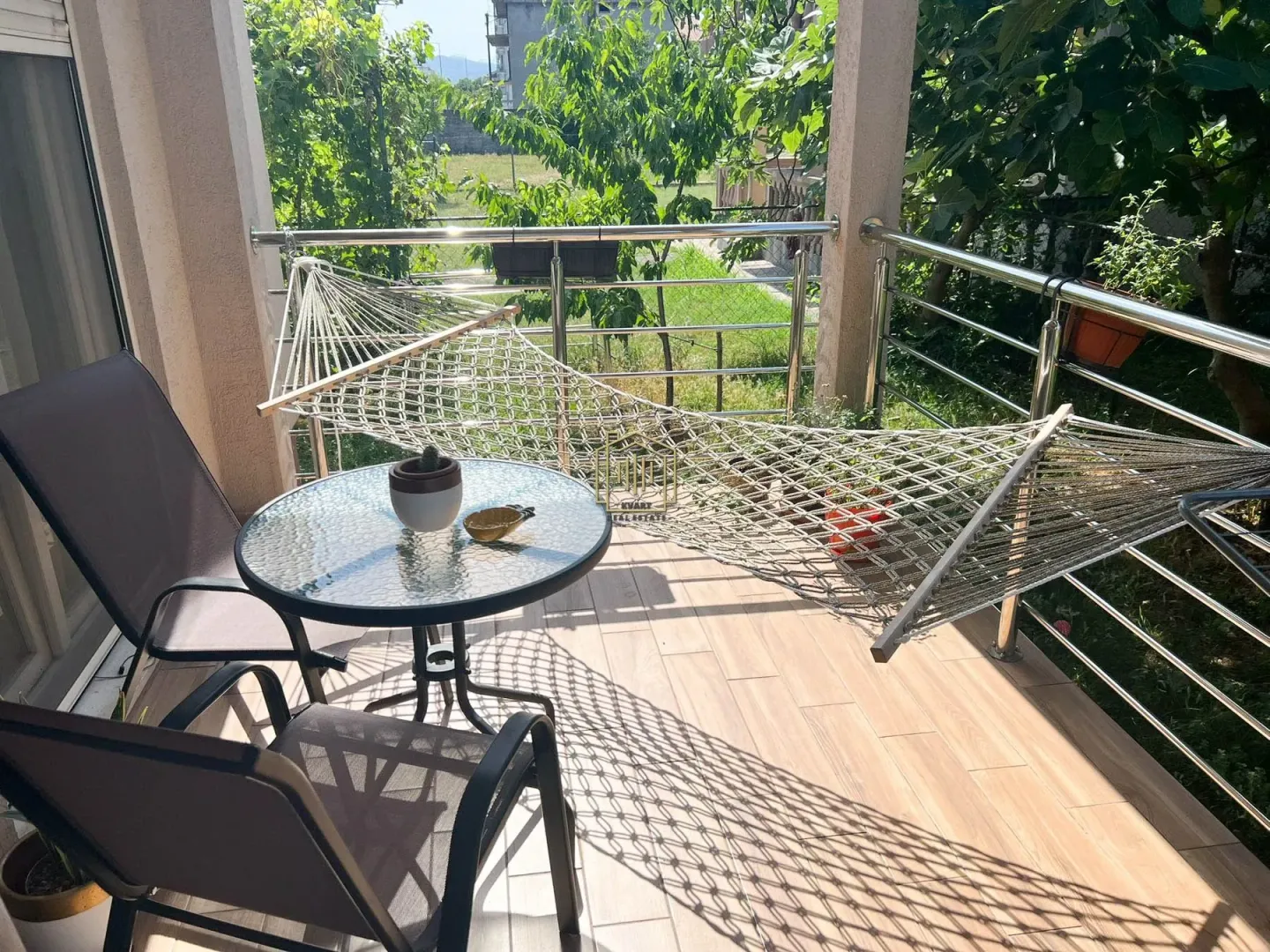 Covered terrace with a table, chairs, hammock, and a view of the yard.