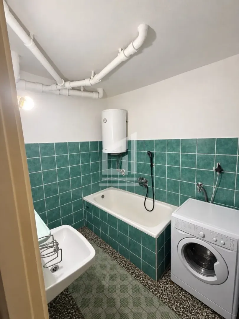 Manje kupatilo sa kadom, umivaonikom, bojlerom i veš mašinom.