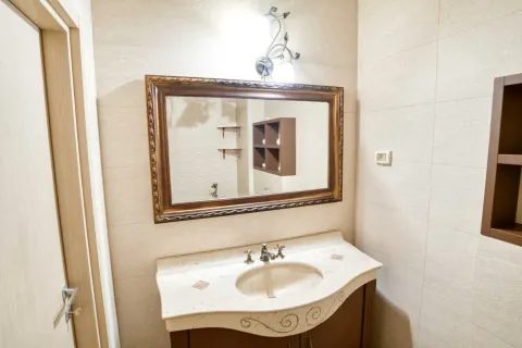 Bathroom with a sink, mirror, and wall tiles. - image 11