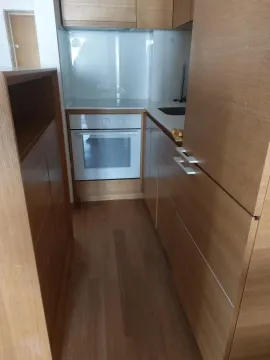 Small wooden kitchen with built-in oven and hob. - image 16