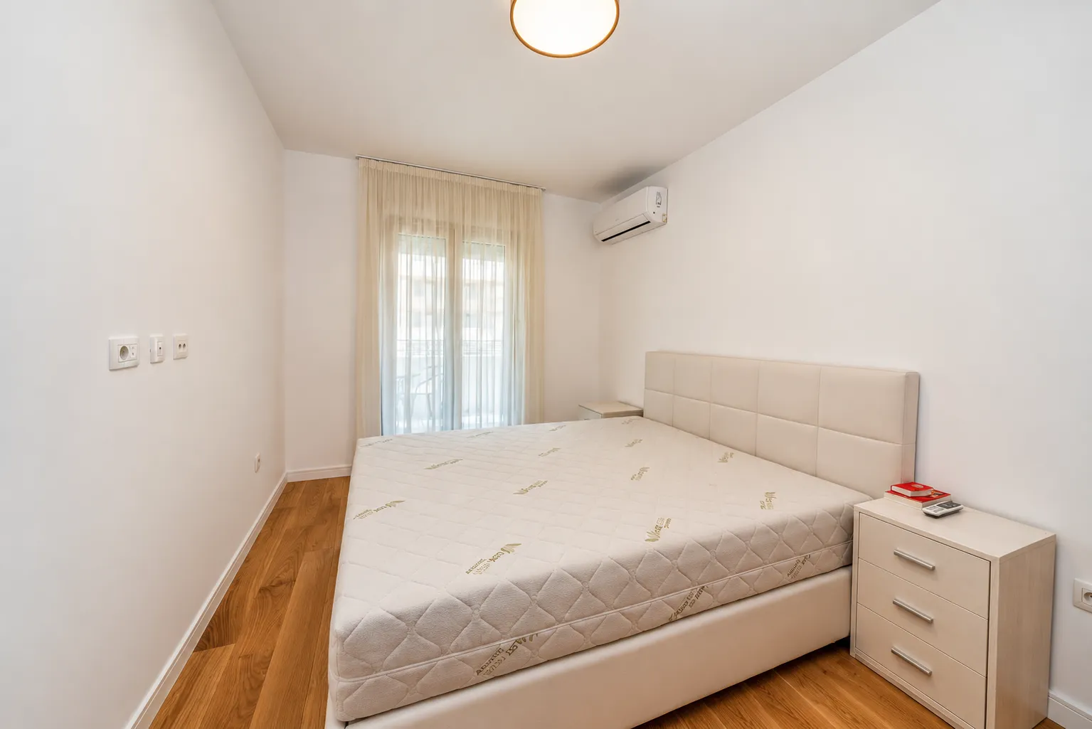 Bedroom with a double bed, bedside tables, and an air conditioning unit.