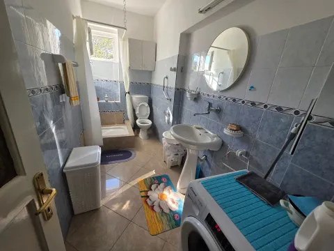 Bright tiled bathroom with a shower cabin, washbasin, and washing machine. - image 19