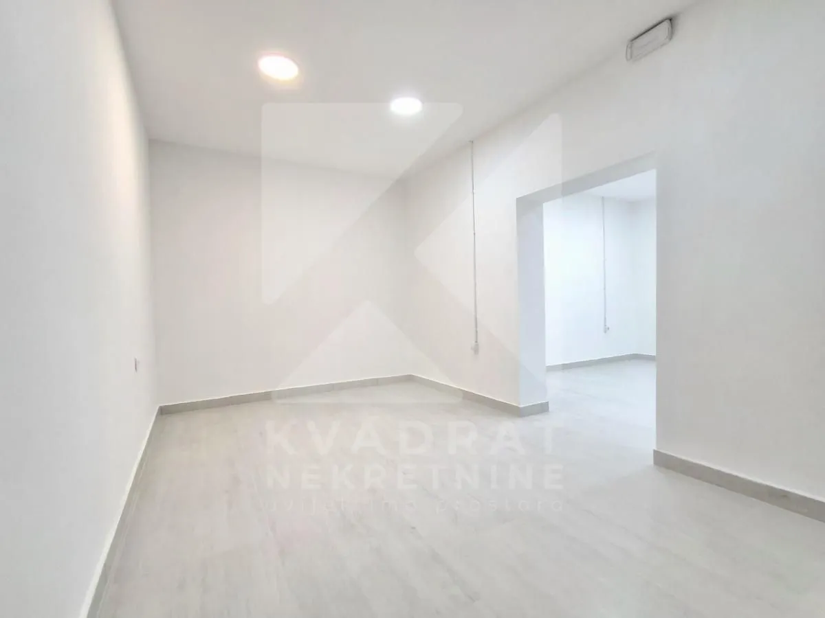 Empty bright room with white walls and laminate flooring.