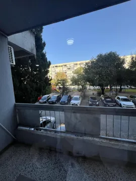 View from the balcony overlooking a parking lot and nearby buildings. - image 13