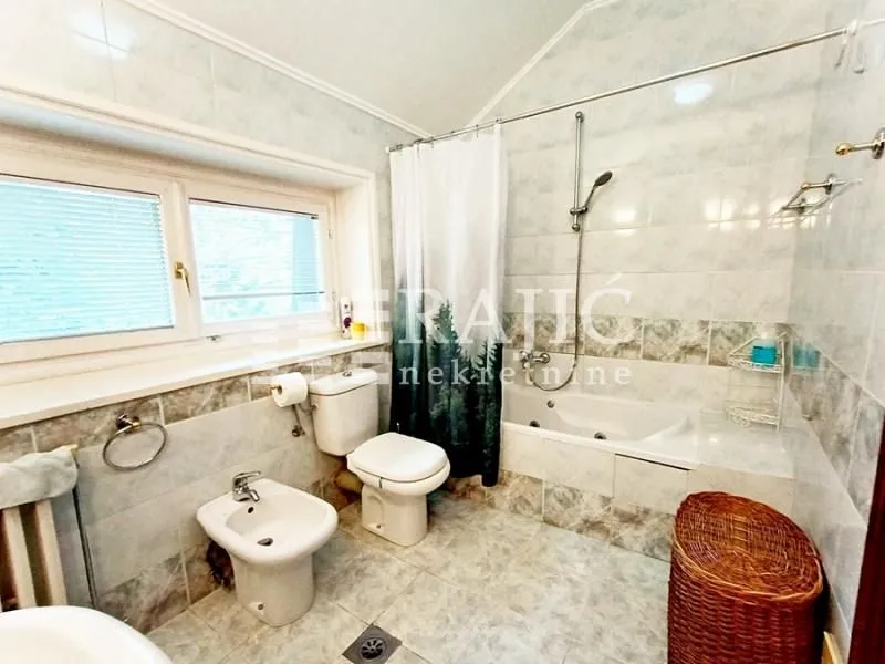 Compact tiled bathroom featuring a bathtub, toilet, and bidet.