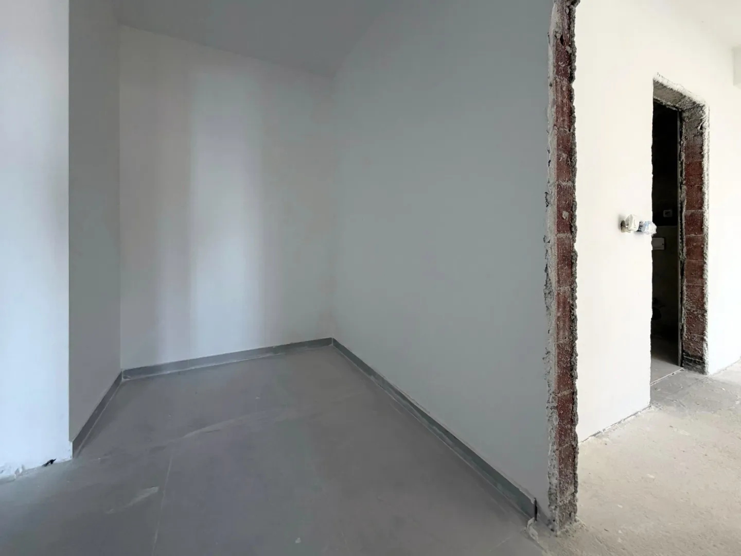 Prazna prostorija u neopremljenom stanu u izgradnji sa postavljenim keramičkim pločicama.