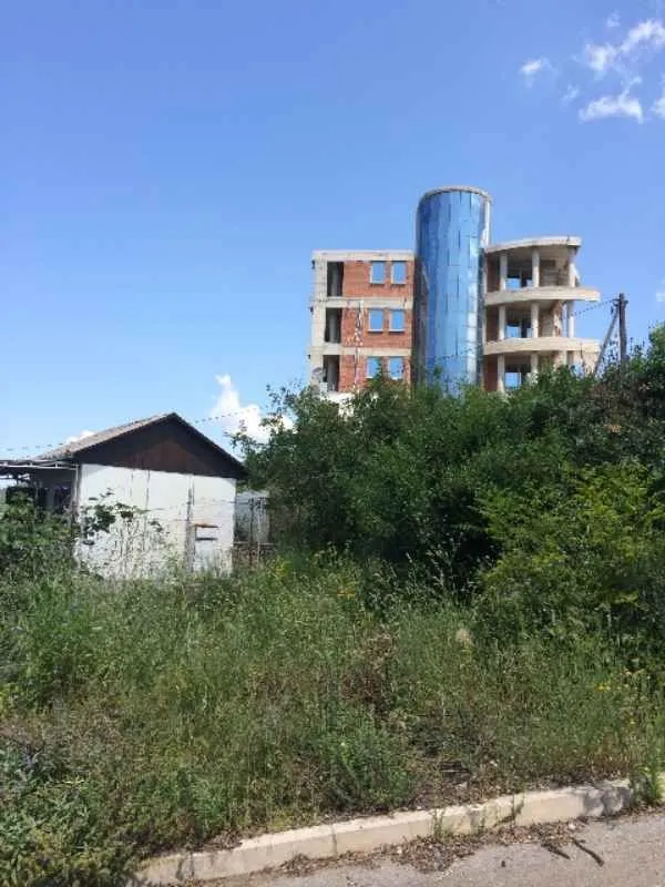 Spoljašnji pogled na plac sa objektom u izgradnji i rastinjem.