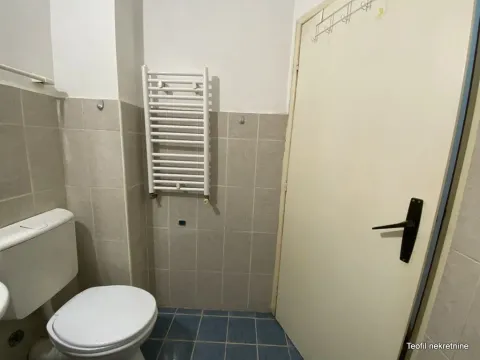 Pogled na kupatilo sa WC šoljom, keramičkim pločicama i vratima. - image 9