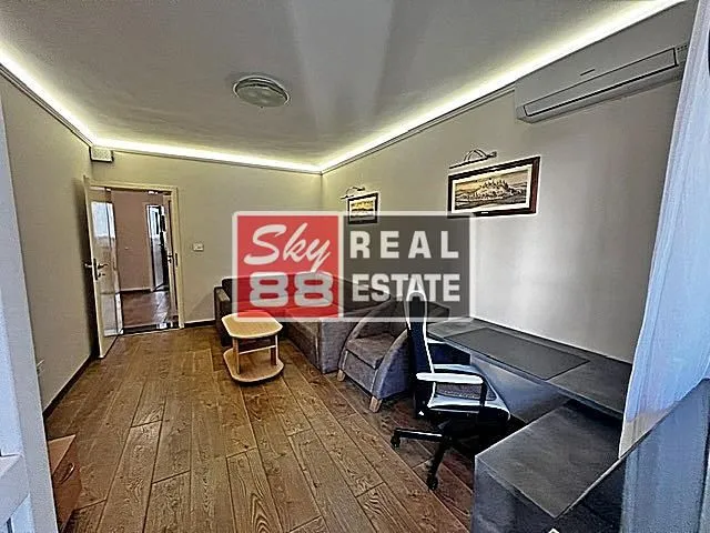 Living room with sofa set, desk, and air conditioning.