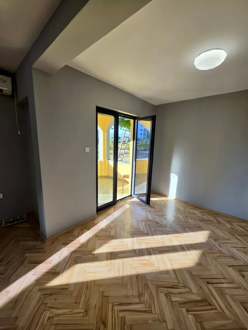 Empty room with wooden parquet flooring and access to a terrace.