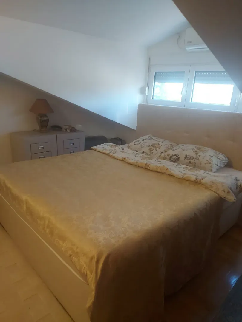 Spavaća soba u potkrovlju sa bračnim krevetom.