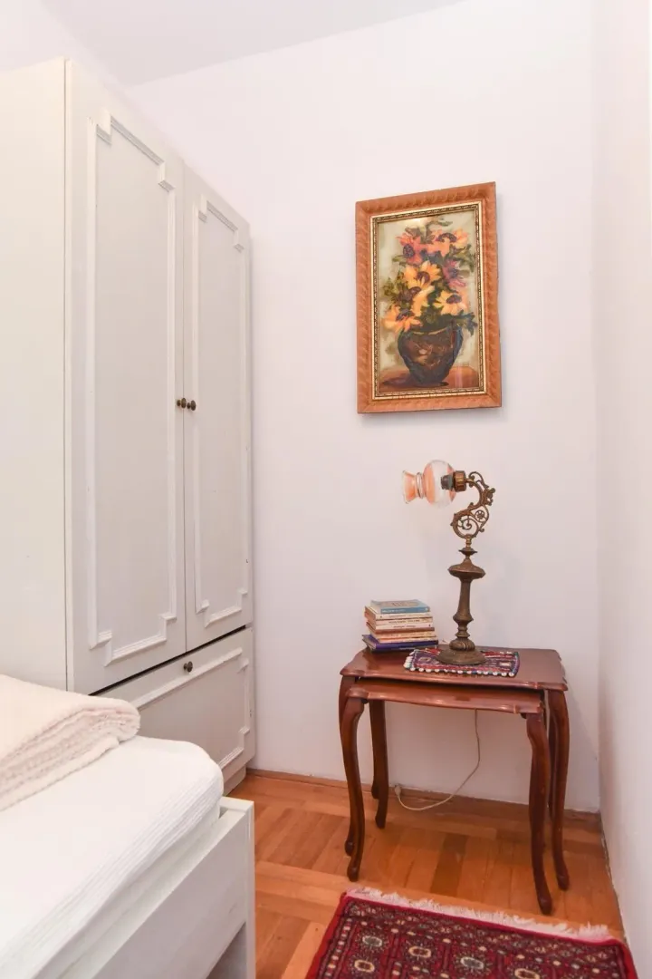 Part of a bedroom with a bed, wardrobe, and a bedside table with a lamp.