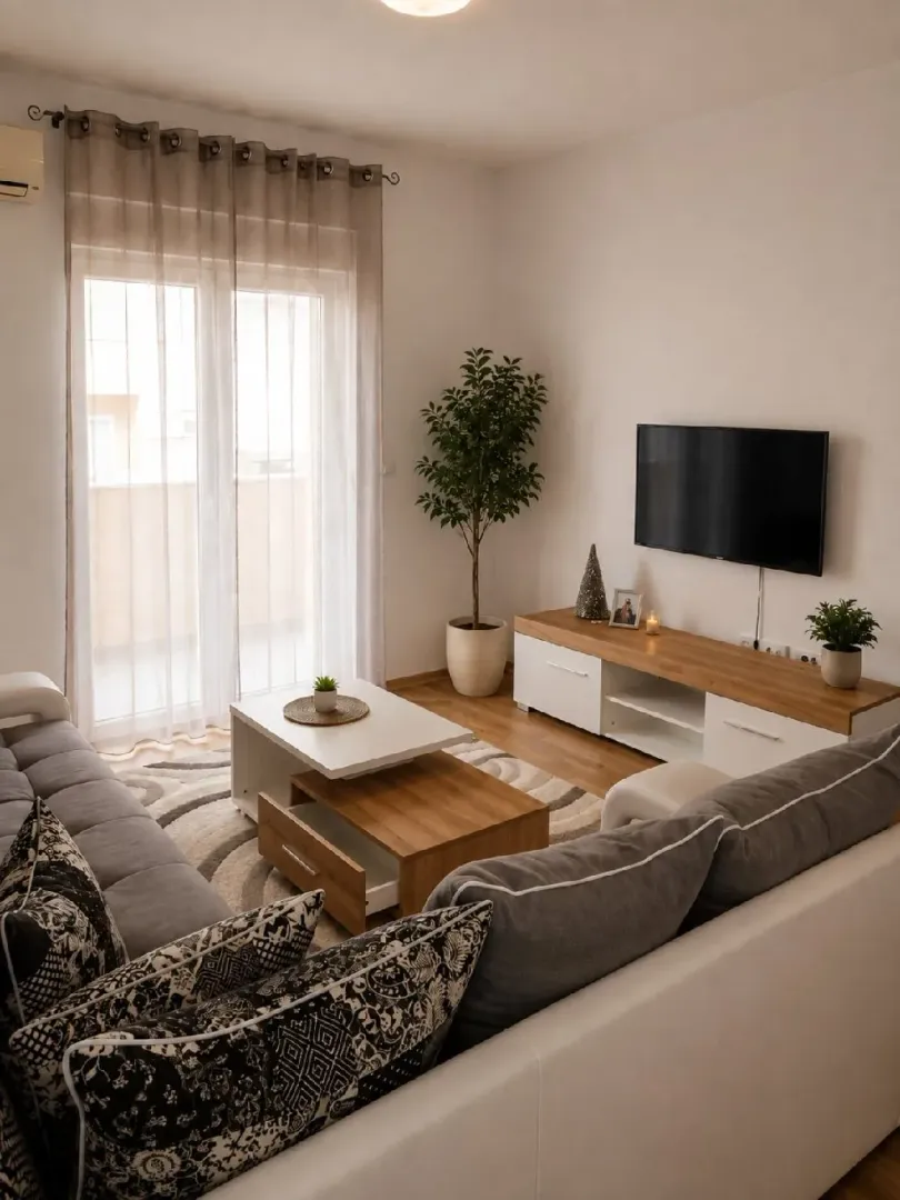 Dnevna soba sa garniturom, TV komodom i izlazom na terasu.
