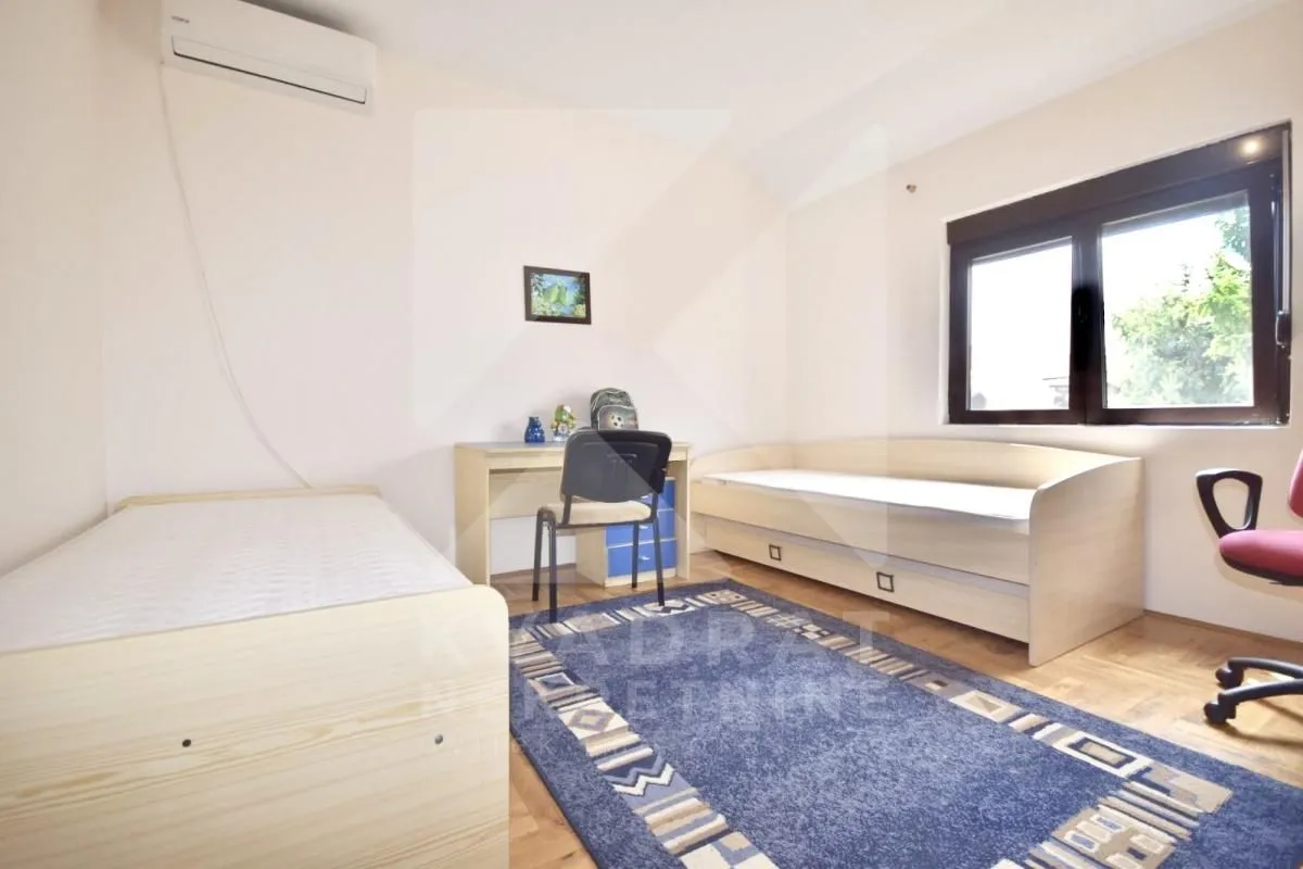 Children's bedroom with two beds, a desk, and an air conditioning unit.