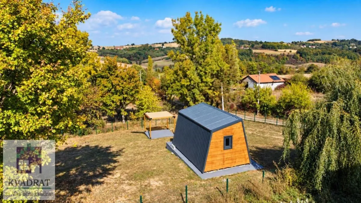 Pogled iz vazduha na malu montažnu kuću u prirodi okruženu zelenilom.