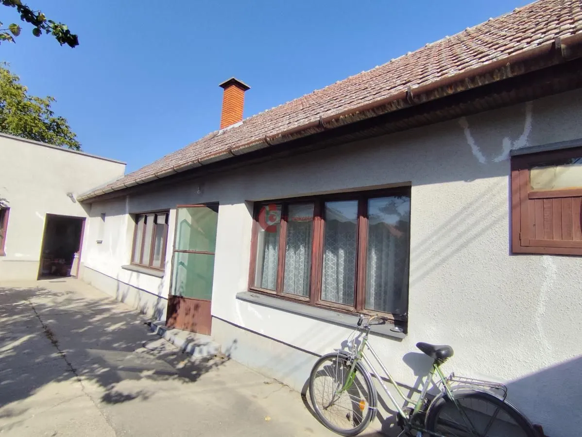 Pogled na spoljašnjost kuće sa dvorištem i biciklom.