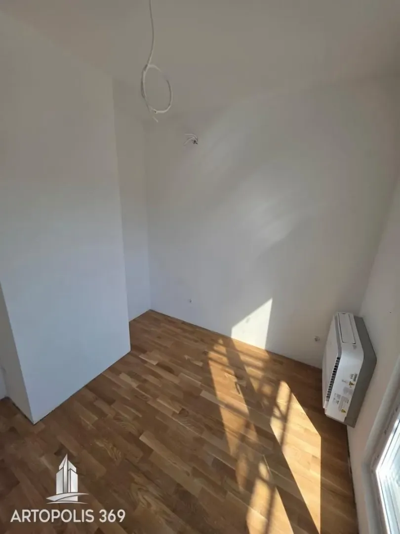 Empty room with wooden parquet flooring and an air conditioner.