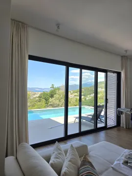Pogled iz dnevne sobe na bazen i okolni pejzaž kroz veliku staklenu stijenu. - image 14