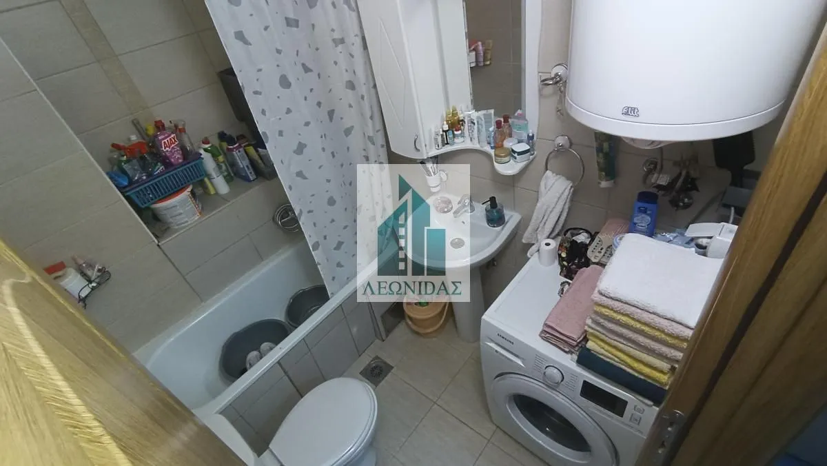 Manje kupatilo sa kadom, umivaonikom, veš mašinom i WC šoljom.