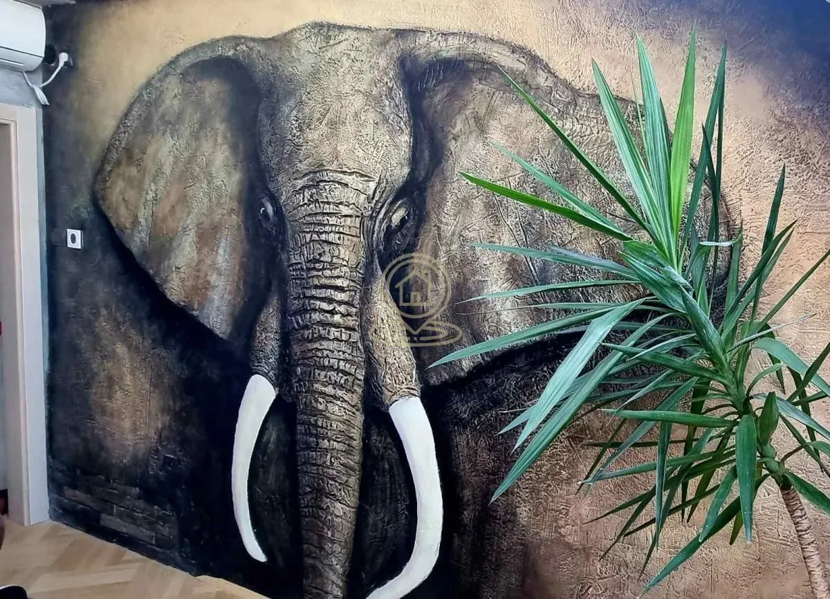 Wall with an elephant artwork and a decorative plant in the room.