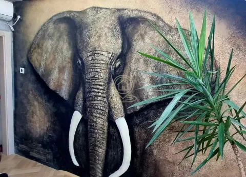 Wall with an elephant artwork and a decorative plant in the room. - image 16