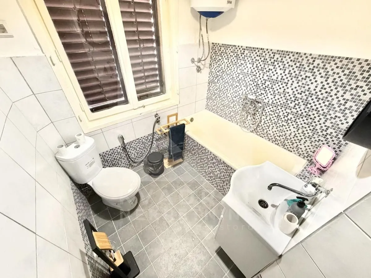 Compact bathroom equipped with a bathtub, washbasin, and toilet.