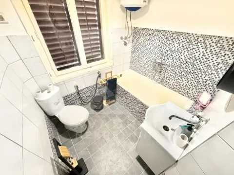 Compact bathroom equipped with a bathtub, washbasin, and toilet. - image 10