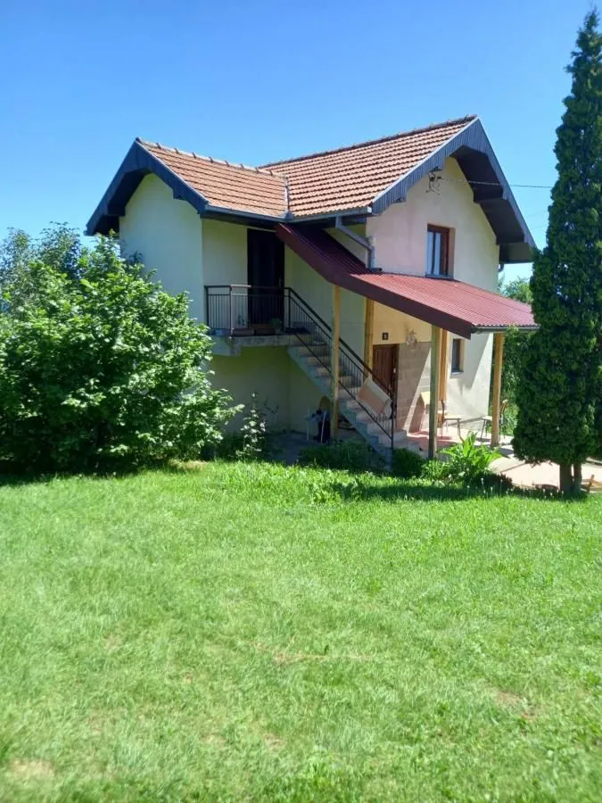 View of a two-story house with external stairs and a landscaped yard.