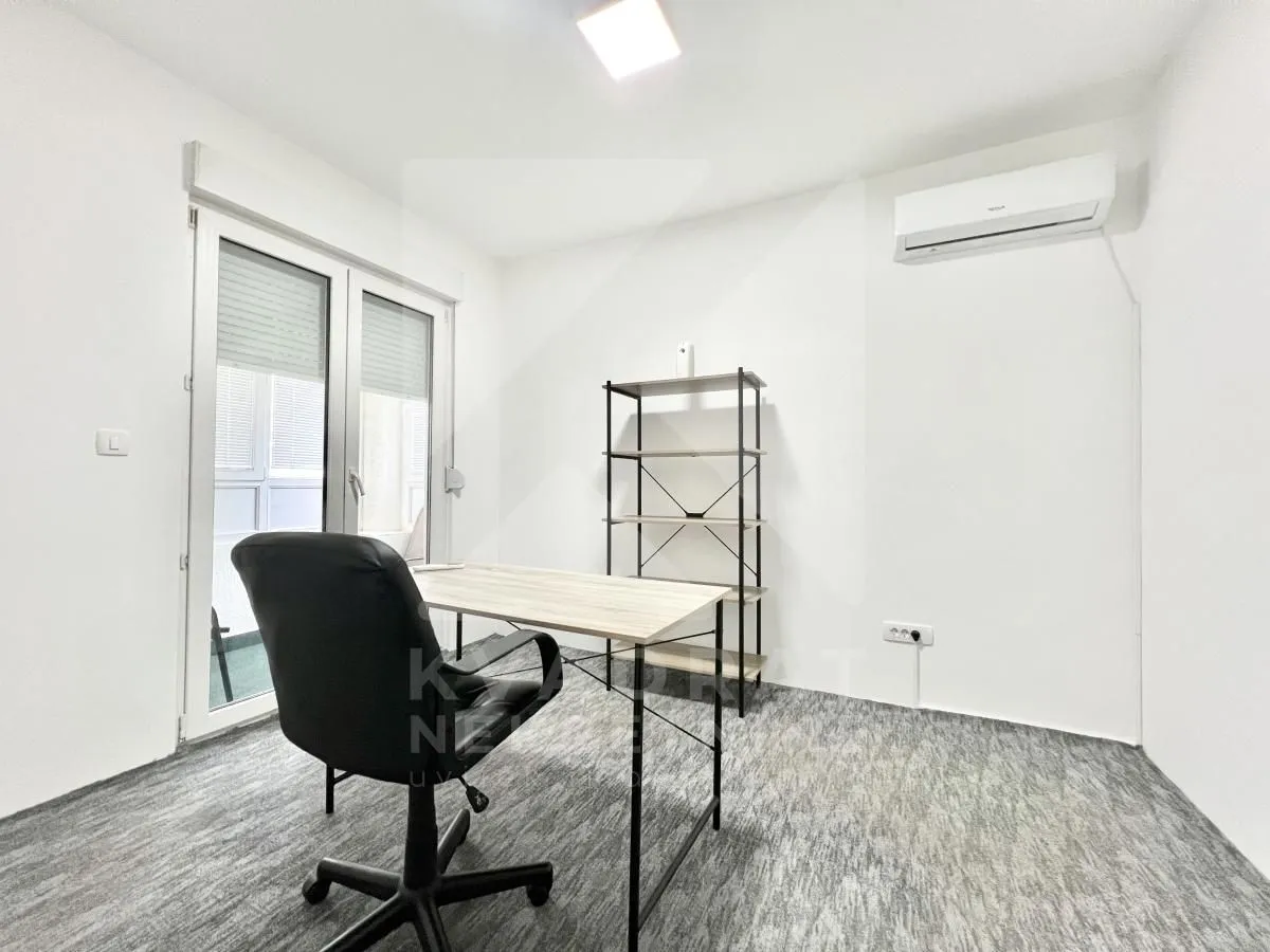 A study room with a desk, office chair, and shelving unit.