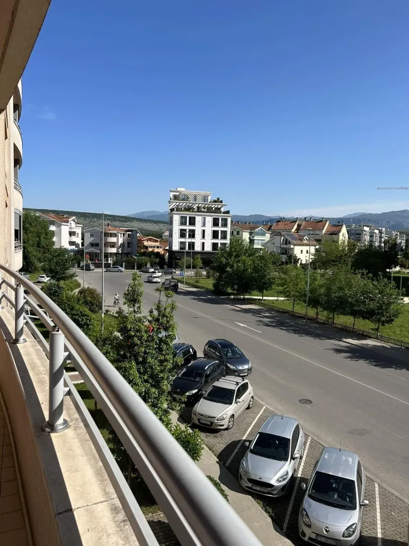 Pogled sa balkona na ulicu i okolne zgrade.