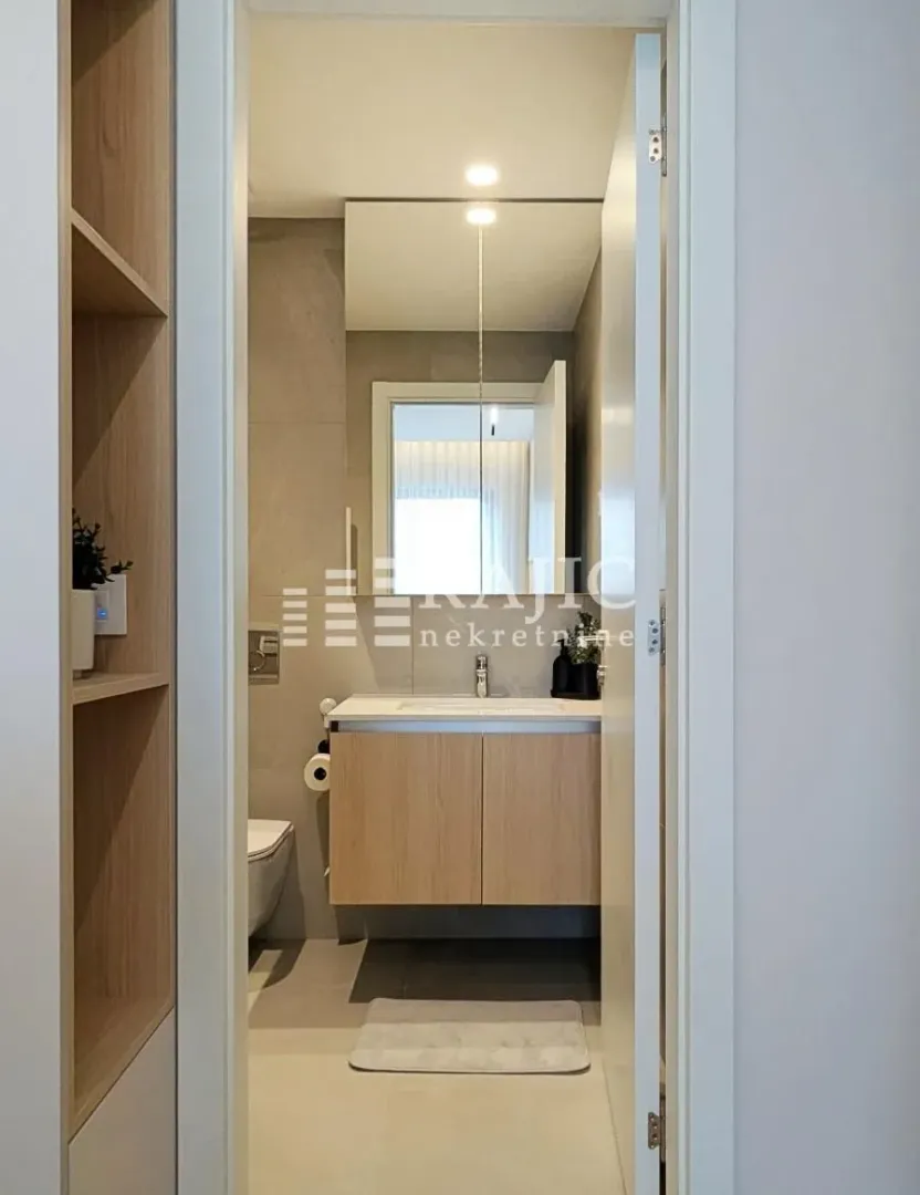 View of a modernly decorated bathroom with a sink and cabinet through the doorway.