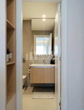 View of a modernly decorated bathroom with a sink and cabinet through the doorway. - image 15