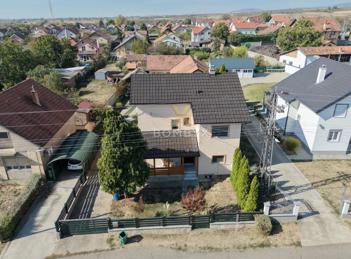 Pogled iz vazduha na porodičnu kuću sa uređenim dvorištem i okruženjem.
