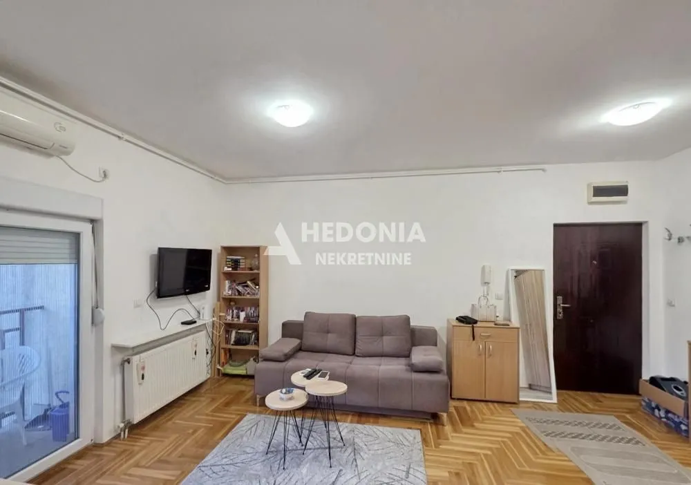 Dnevna soba sa garniturom, televizorom i izlazom na terasu.