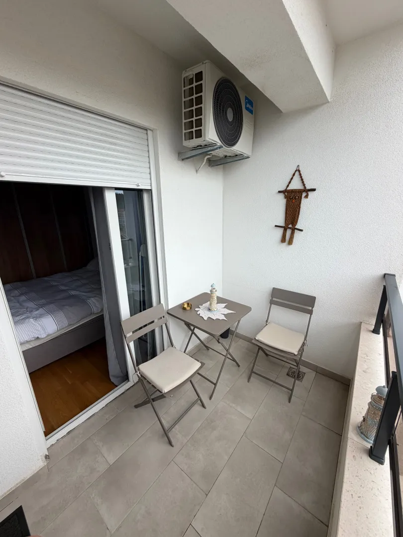 Furnished balcony with seating set and a view into the room interior.