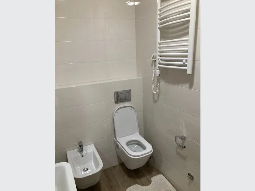 Svijetlo opremljeno kupatilo sa bijelim pločicama i sanitarijama.