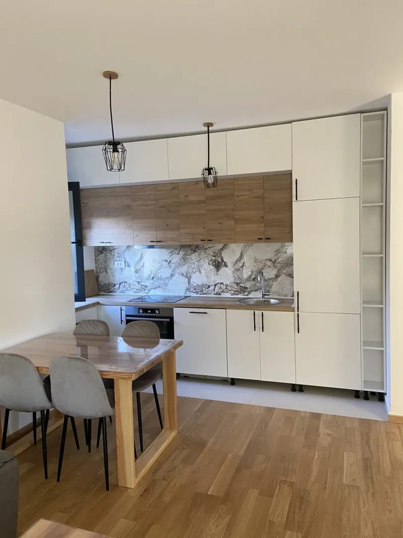 Svijetla moderna kuhinja sa drvenim detaljima i trpezarijskim stolom.