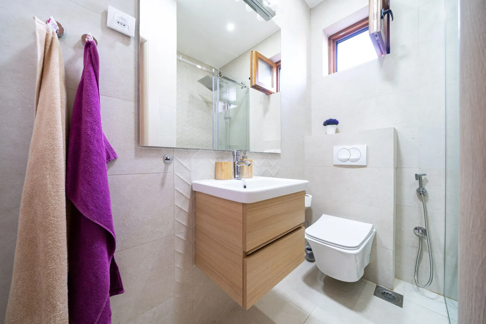 Modernly equipped bathroom with a shower cabin, washbasin, and toilet.