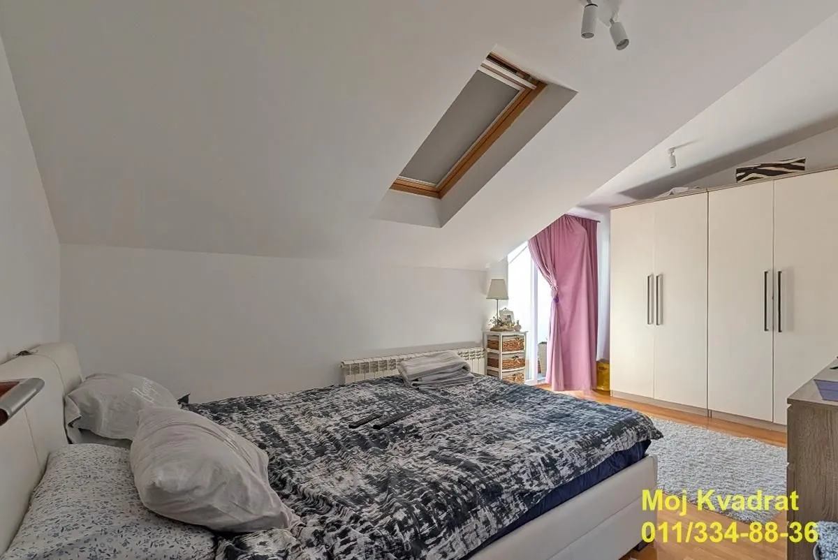 Attic bedroom with a double bed, wardrobe, and a skylight.