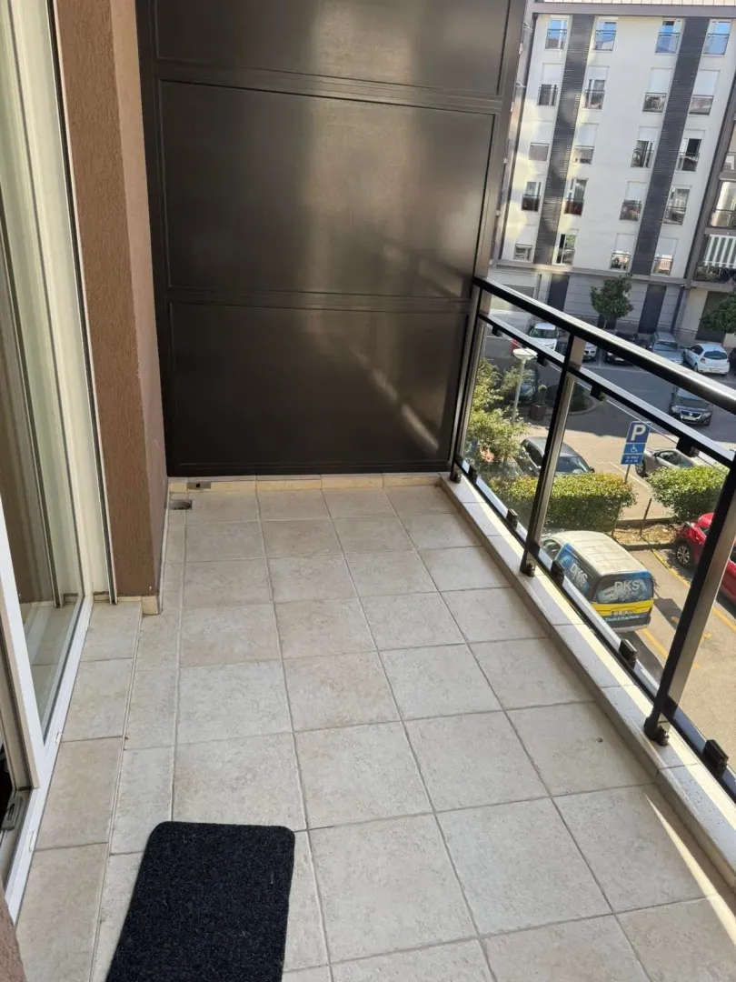 Manji popločani balkon sa ogradom i pogledom na ulicu.