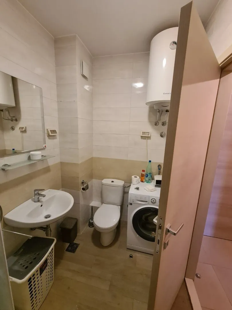 Kupatilo sa veš mašinom, ogledalom i lavaboom.