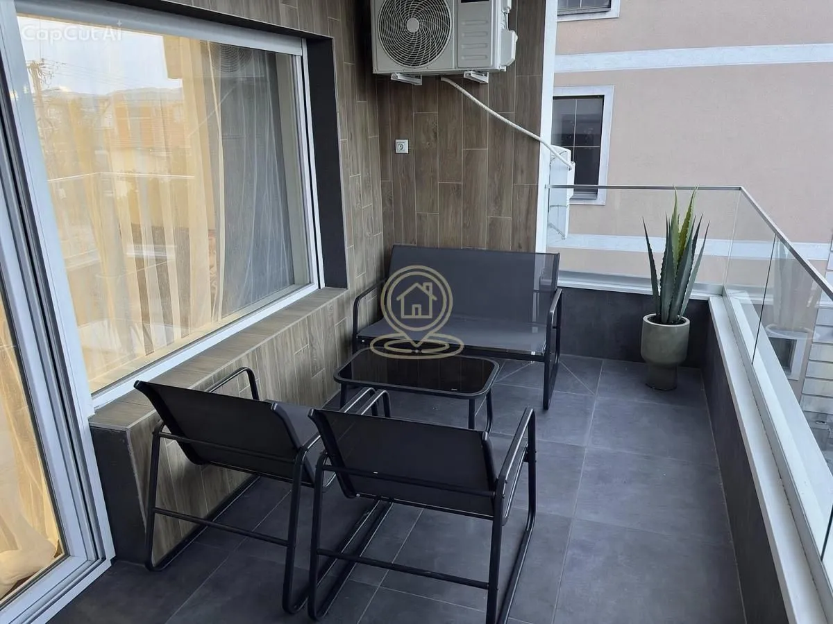Nameštena terasa sa garniturom za sedenje i staklenom ogradom.