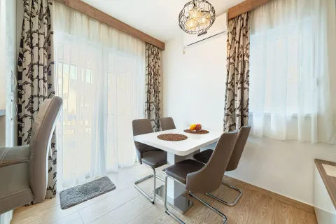 Dining area with a white table and modern brown chairs next to balcony doors. - image 12