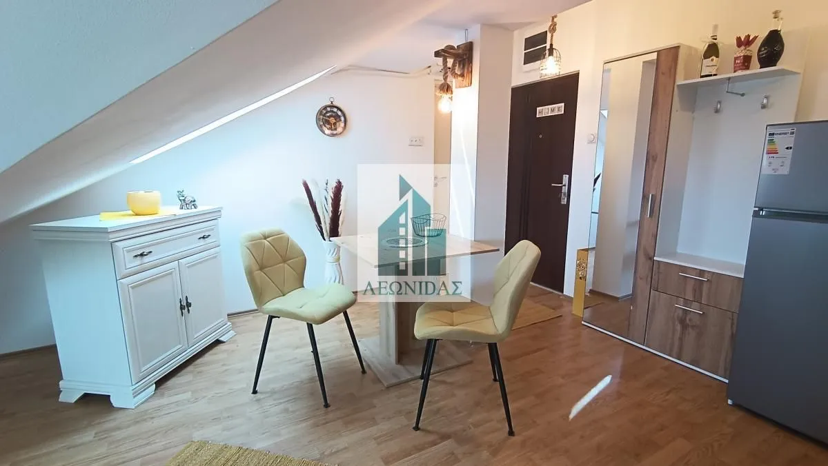 Small living room with a dining table, chairs, and a dresser under a sloped ceiling.