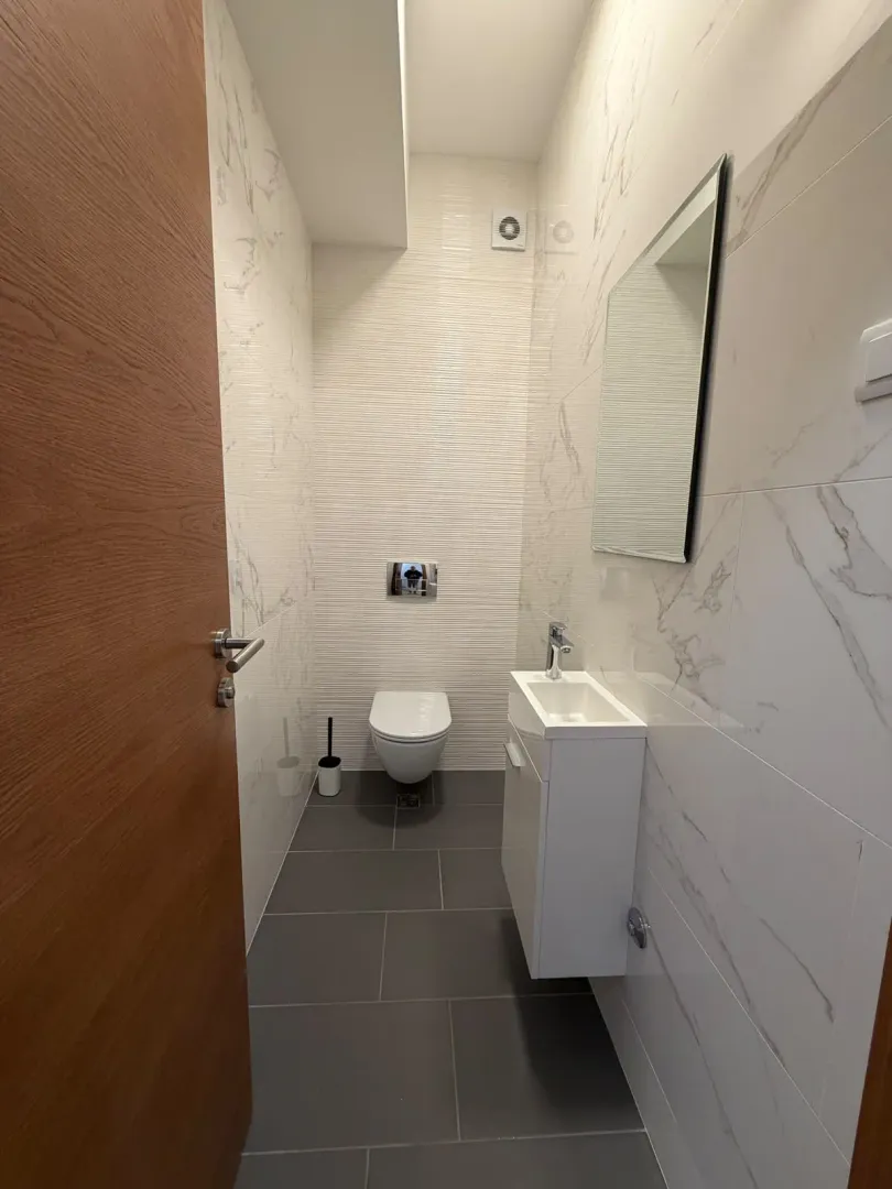 Savremeno opremljeno kupatilo sa WC šoljom i umivaonikom.