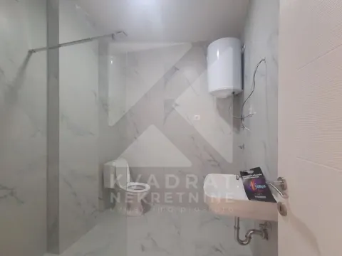 Small bathroom tiled with marble-look tiles featuring a walk-in shower, toilet, and washbasin. - image 22