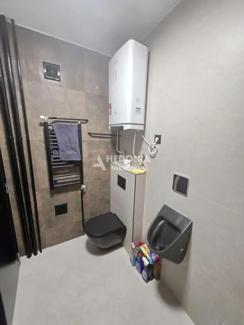 Moderno kupatilo sa WC šoljom, pisoarom i bojlerom.