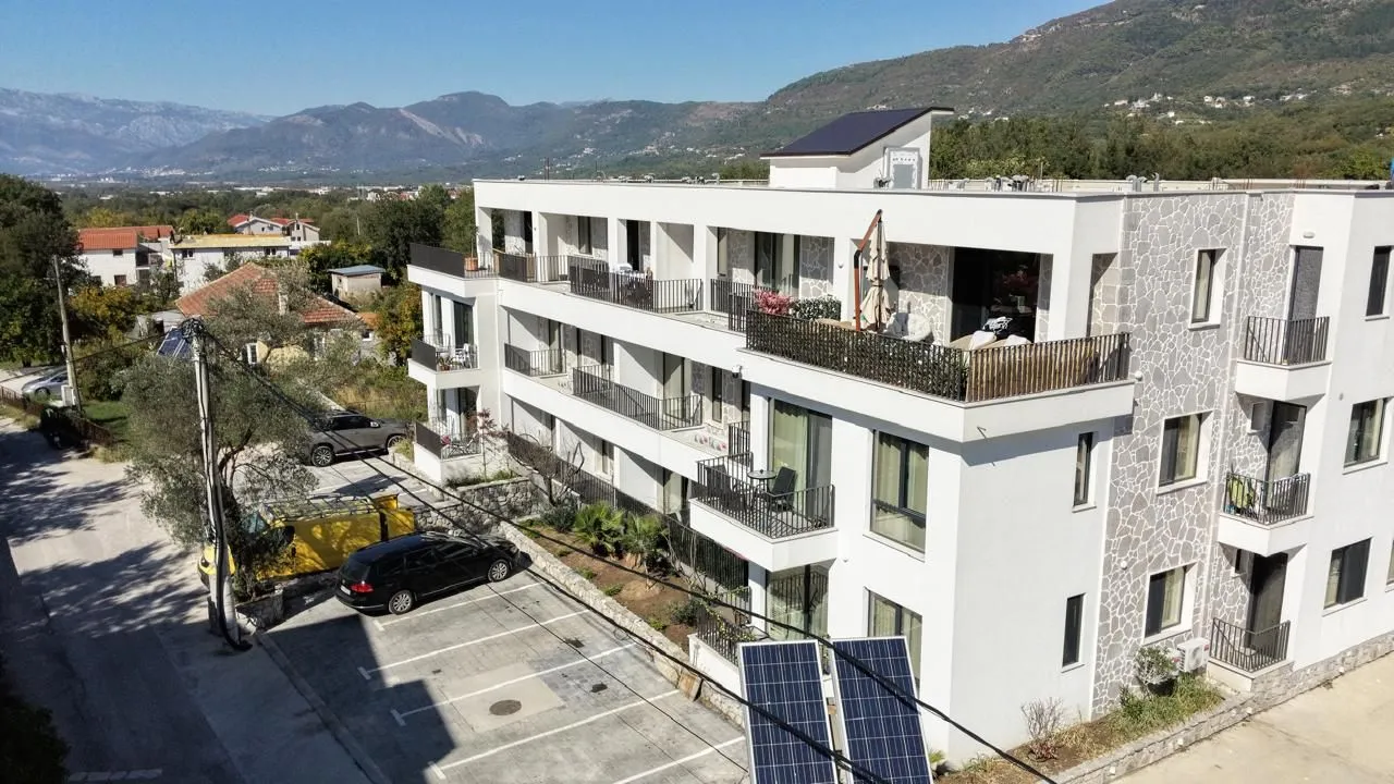 Aerial view of a modern residential building with parking and surroundings.