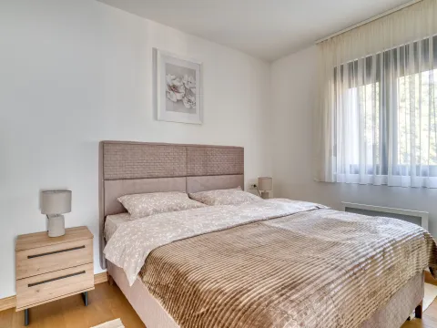 Spavaća soba sa bračnim krevetom, noćnim stočićem i prozorom sa zavjesama. - image 14