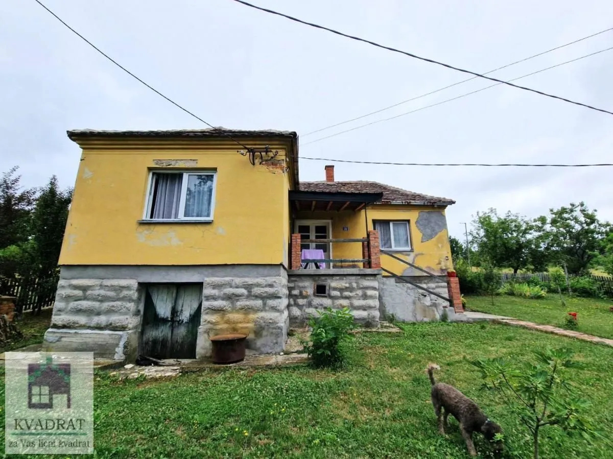 Pogled na stariju prizemnu kuću žute fasade sa dvorištem.